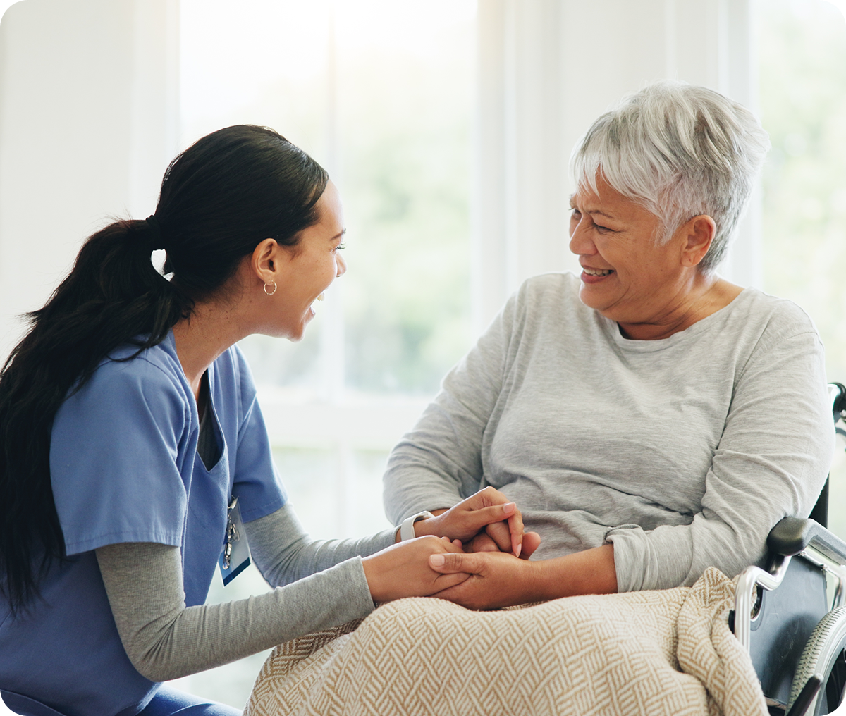 Caregiver smiling with elderly woman in wheelchair