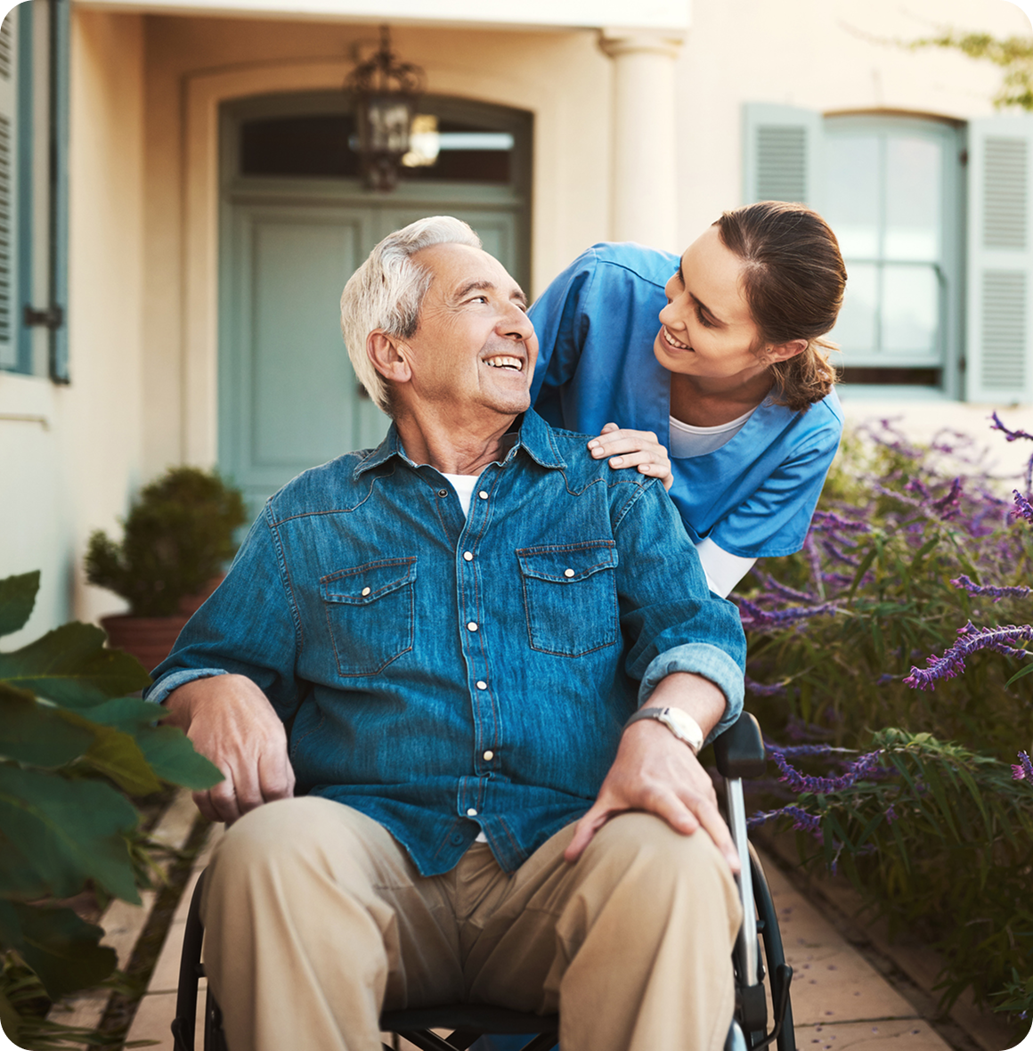 Elderly man in wheelchair with caregiver smiling