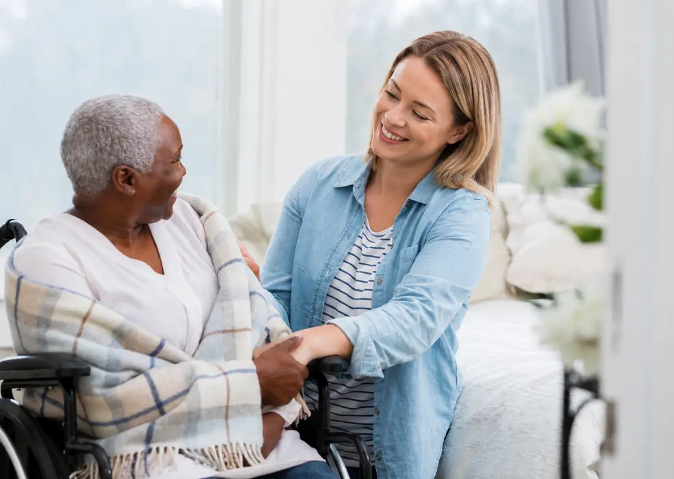 Woman smiling with elderly person in wheelchair